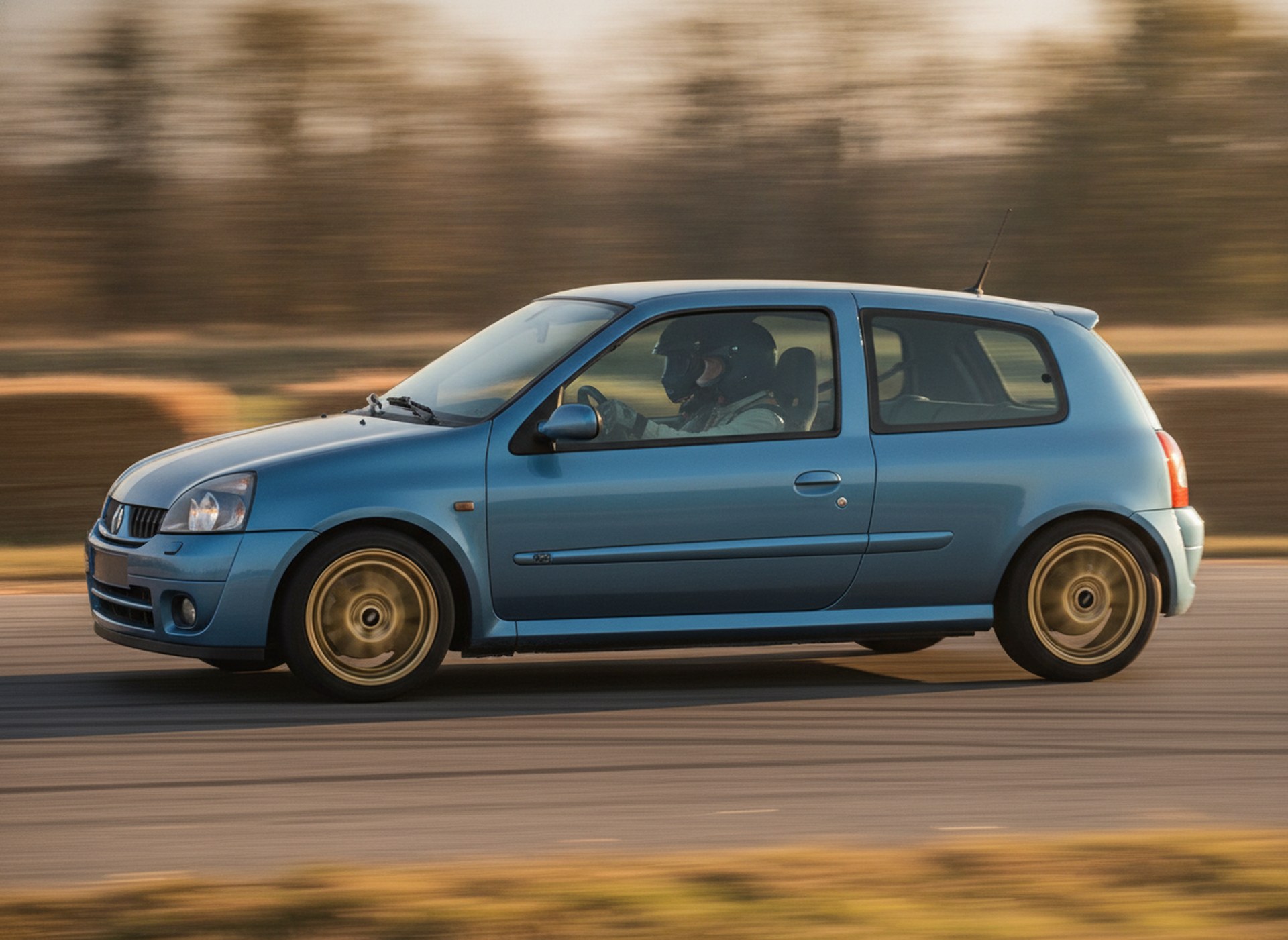 Blue Renault Clio MK1 driven hard through a corner on a rally stage, driver in a plain black helmet