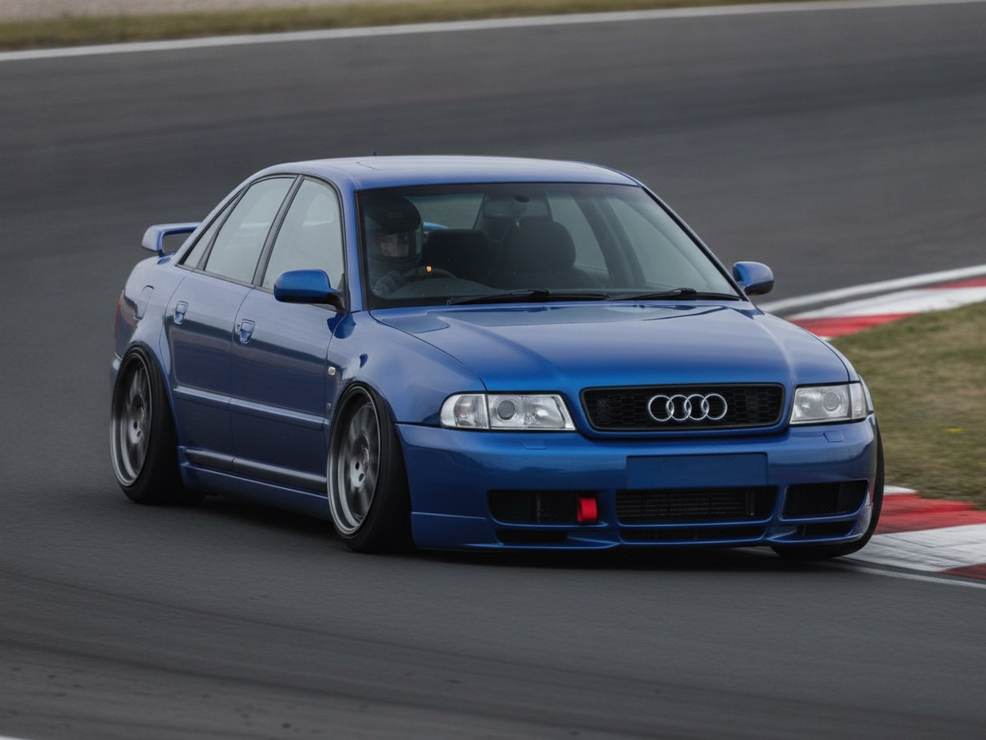 Silver Audi S4 B5 saloon on a race circuit, driver in a plain black helmet, big brake kit guide