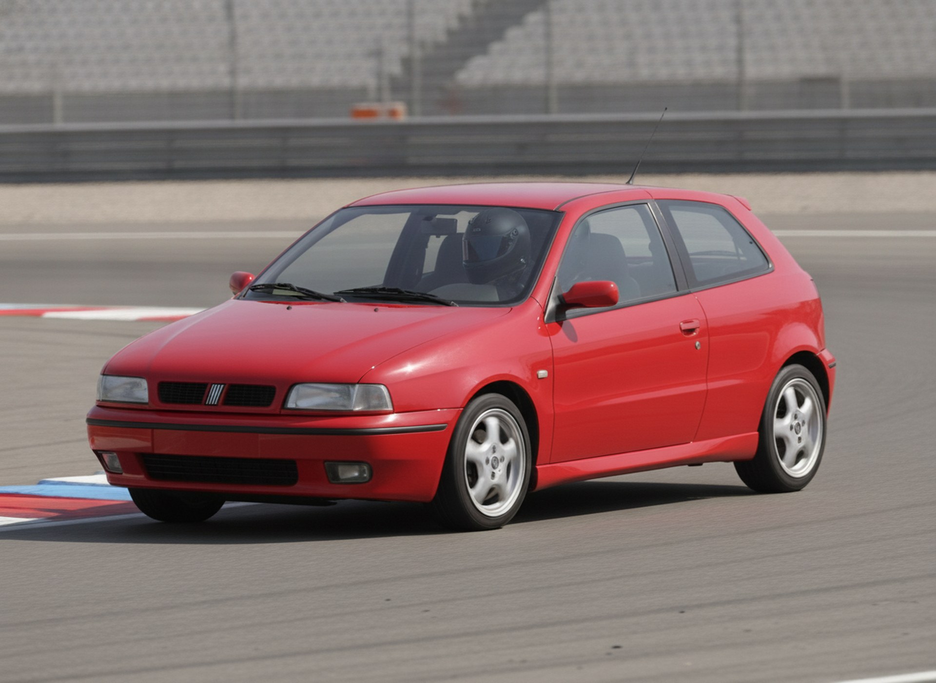 Red Fiat Bravo being driven on a race circuit, driver in a plain matte black full-face helmet