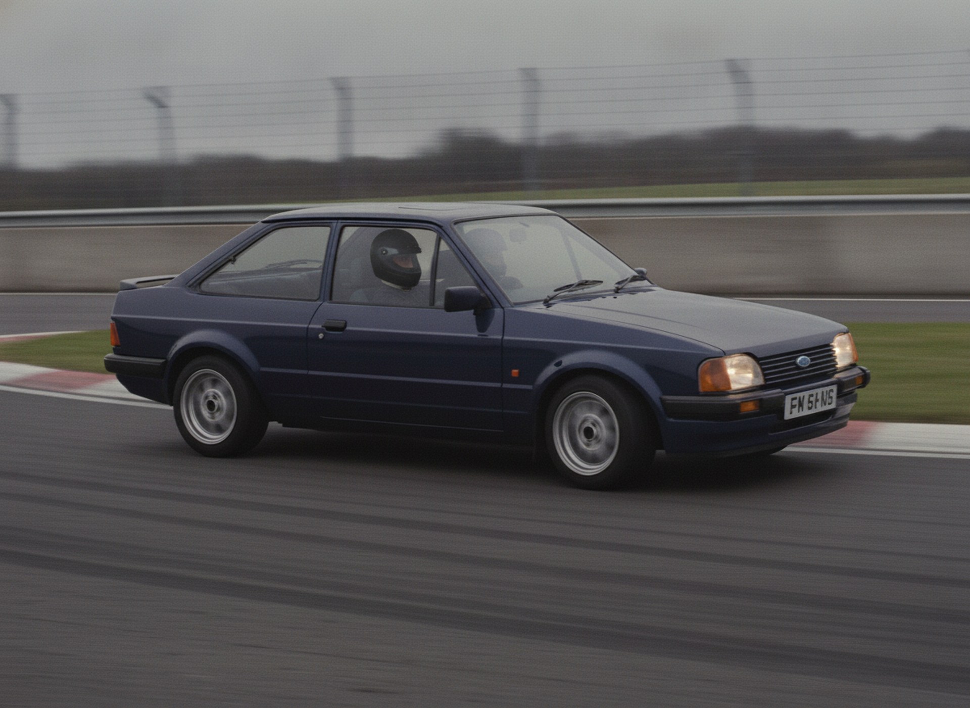 Ford Escort MK4 being driven hard through a circuit corner, driver in a plain matte black racing helmet