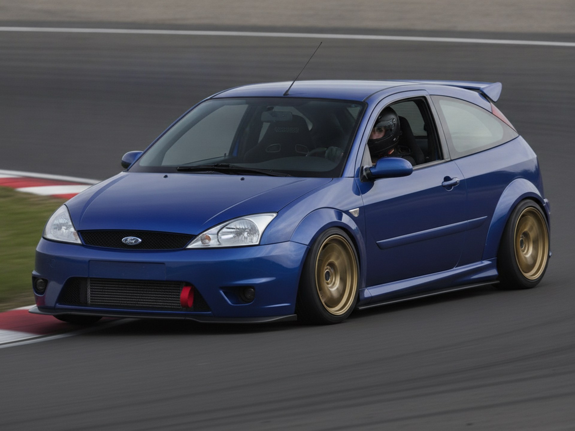 Blue Ford Focus RS Mk1 being driven hard through a corner on a race circuit, driver in a plain black helmet