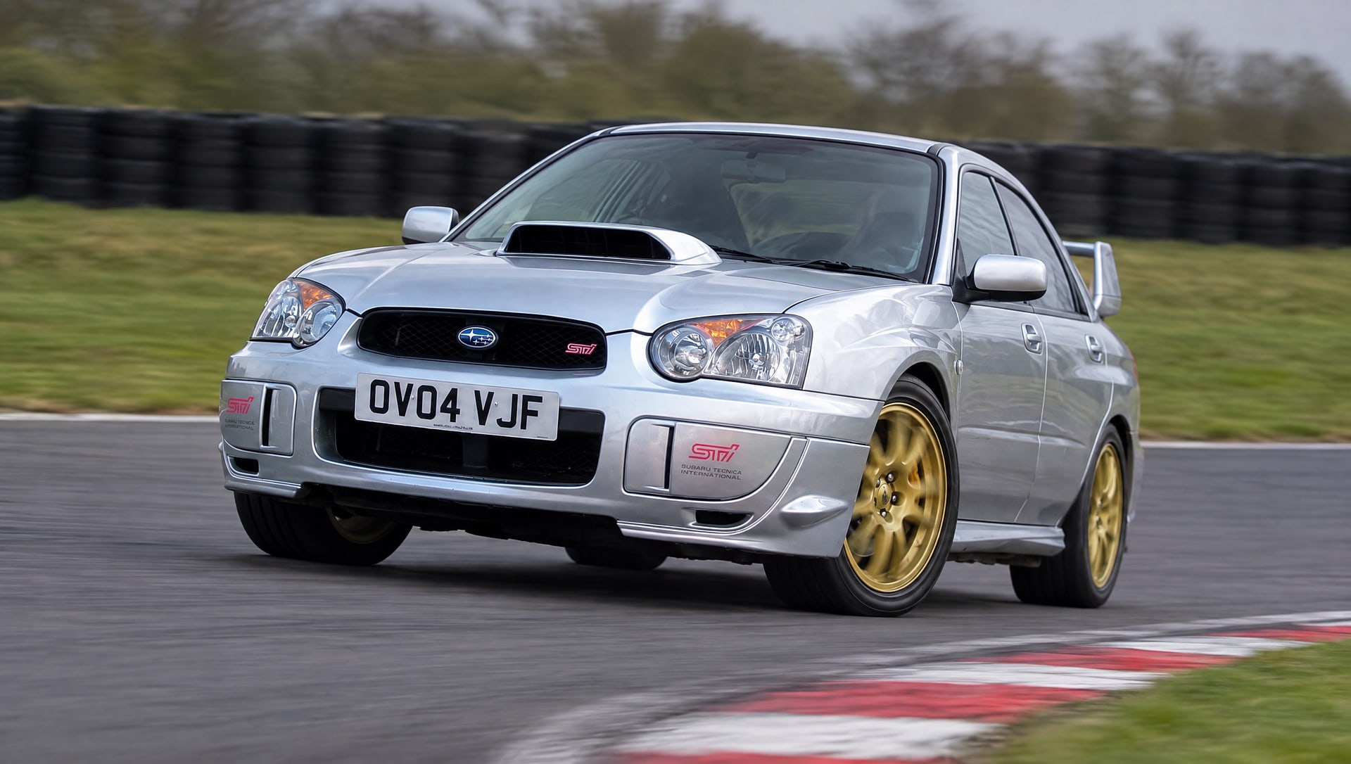 Silver 2004 Subaru Impreza WRX STI, registration OV04 VJF, cornering on a UK race circuit on a track day