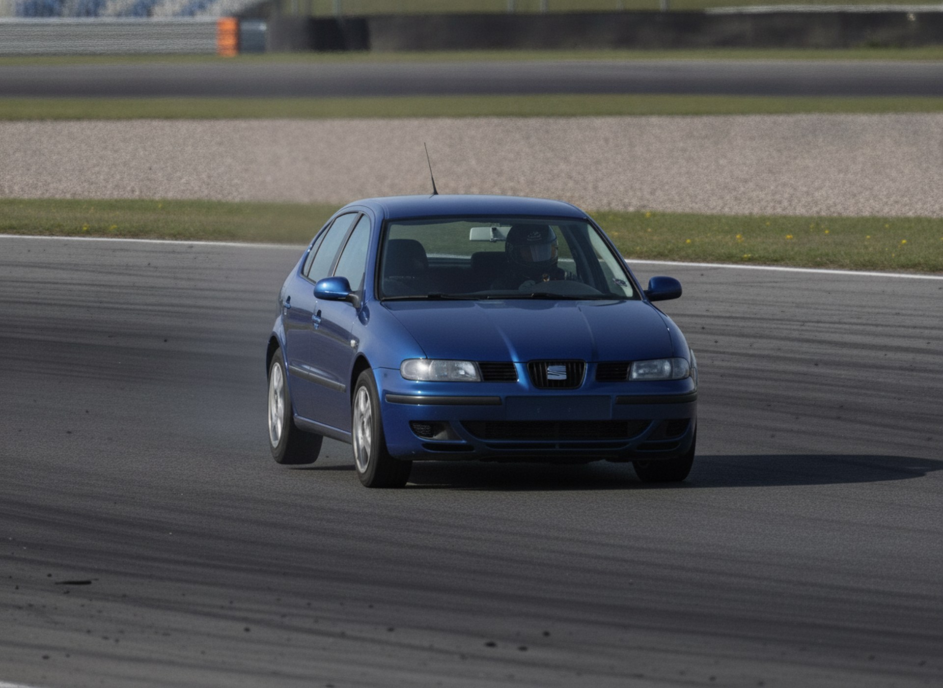Seat Leon MK1 on circuit at speed, driver in plain black racing helmet