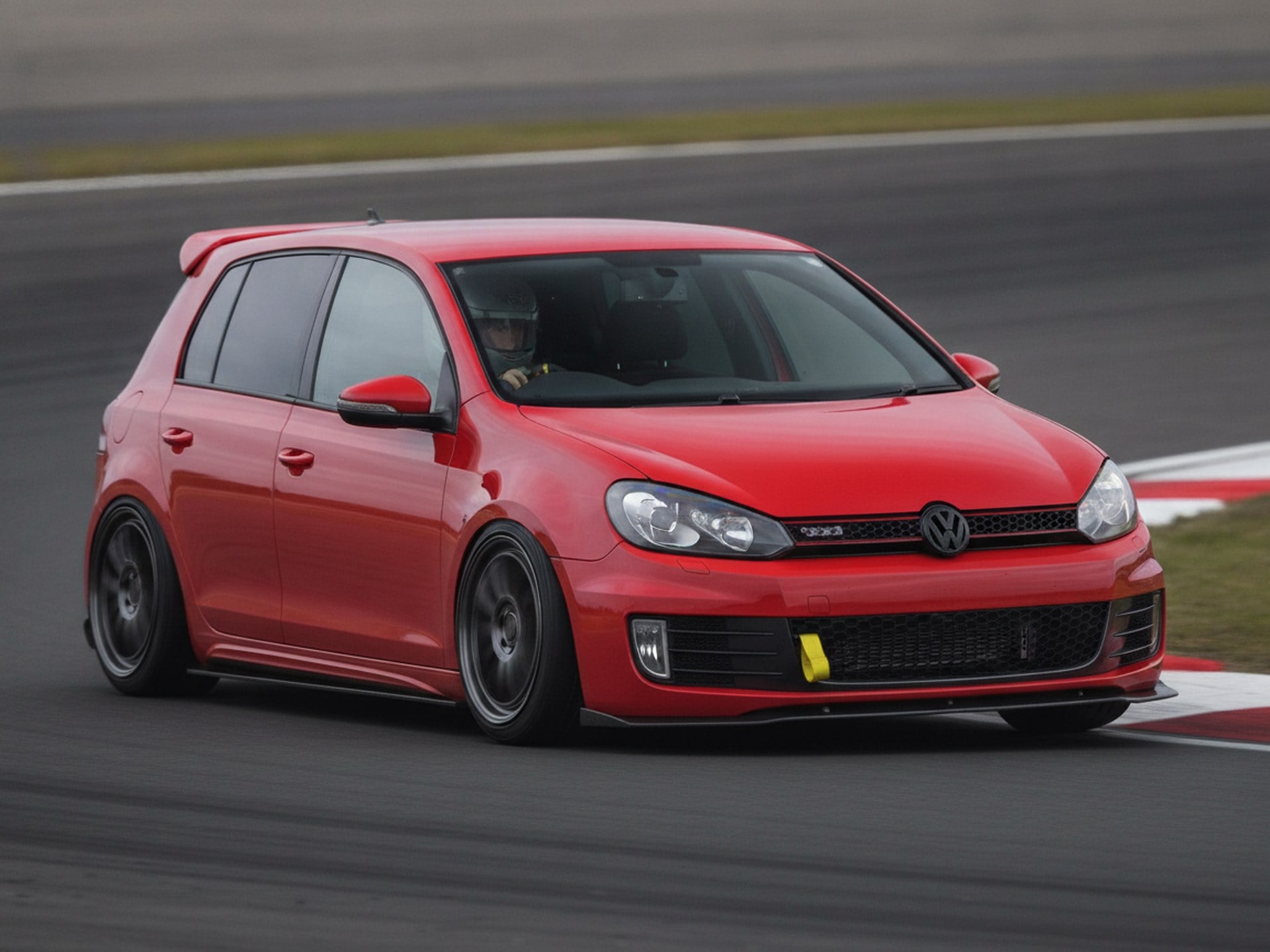 Red Volkswagen Golf MK6 being driven hard through a corner on a race circuit