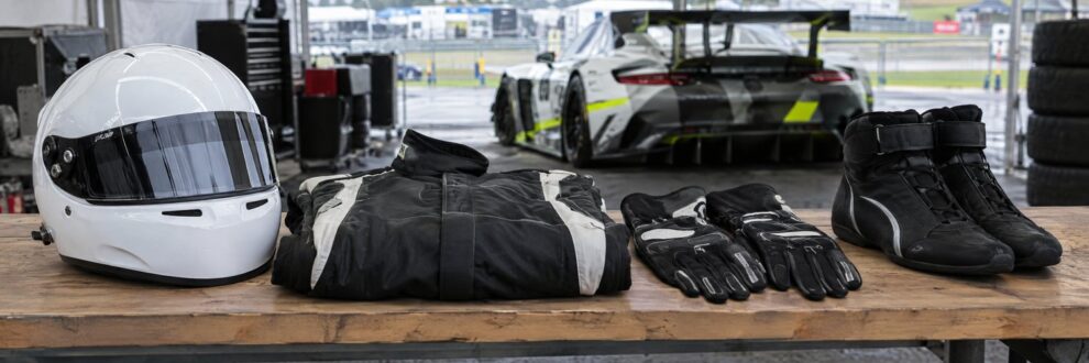 Helmet, race suit, gloves and boots laid on a paddock bench